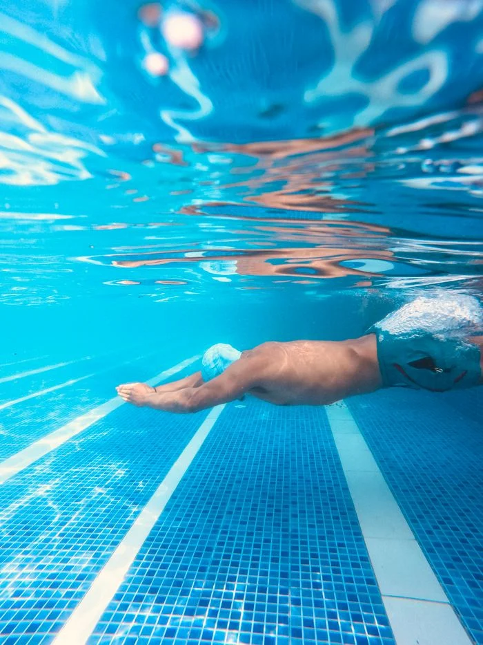 Man swimming underwater in a clear blue pool in Nepal, capturing leisure and fitness.