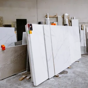 Wide view of granite and marble slabs neatly arranged in a factory setting, showcasing variety and texture.